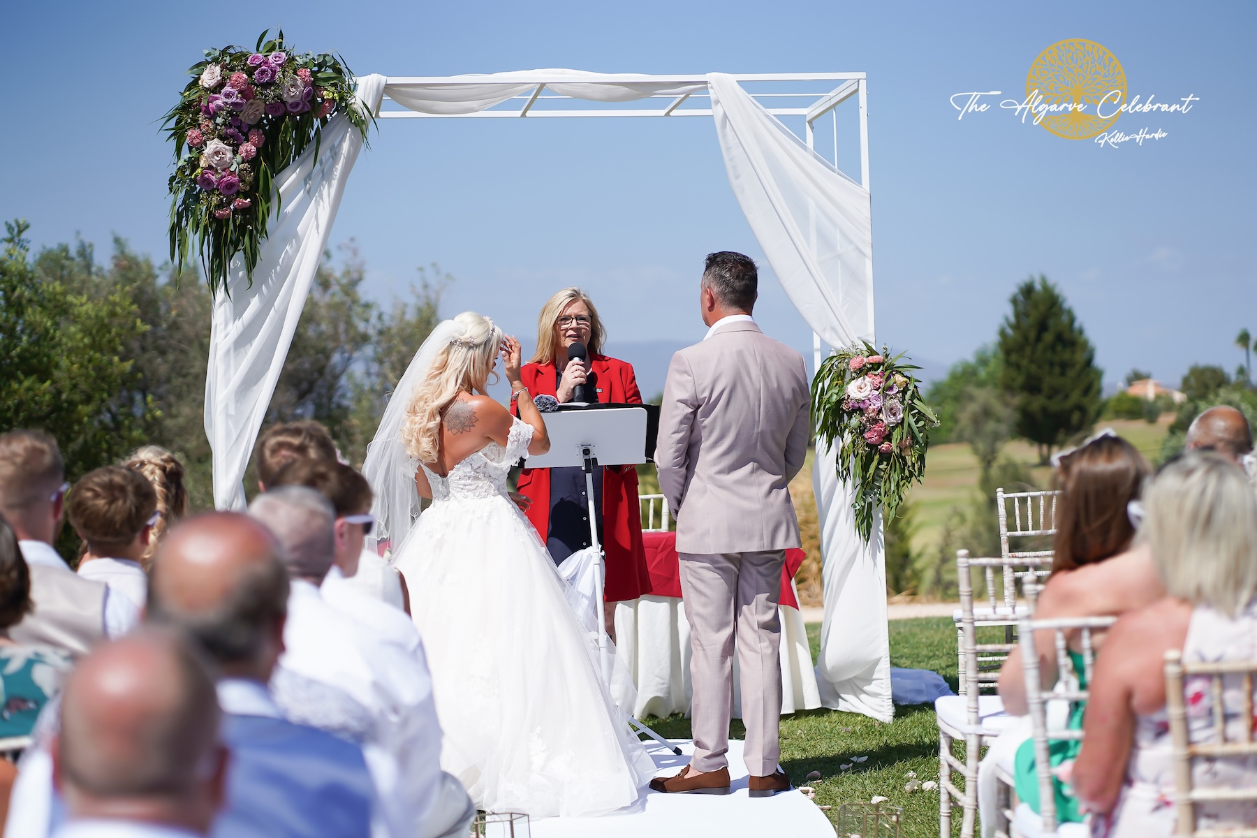 A picturesque outdoor ceremony under the Algarve sun, with Clare and Paul standing hand in hand, surrounded by family and friends in a stunning venue filled with love and joy.