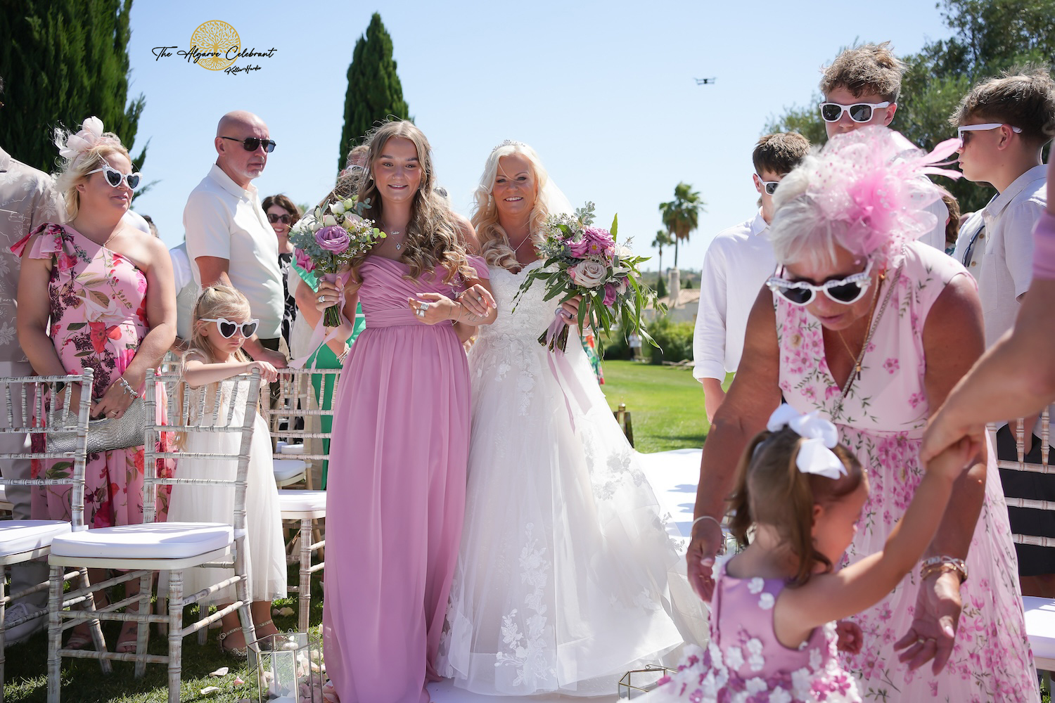 A picturesque outdoor ceremony under the Algarve sun, with Clare and Paul standing hand in hand, surrounded by family and friends in a stunning venue filled with love and joy.